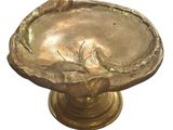 une assiette en or ornée d'un oiseau, posée sur un socle