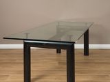 une photo d'une table en verre aux pieds noirs posée sur un parquet