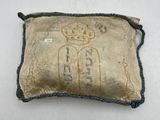 an old pillow with a crown on it sitting on a table