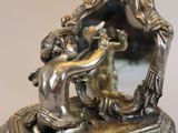 a silver figurine of a man and a woman in a mirror