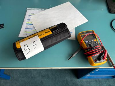 a yellow and black multimeter sitting on a table next to a pair of scissors and a piece of paper
