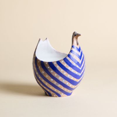 un petit vase bleu et blanc surmonté d'un oiseau