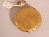 a gold pocket watch that is on display on a table