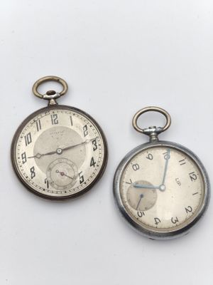deux montres de poche en argent posées l'une à côté de l'autre sur une surface blanche