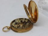 a gold pocket watch with a gold case on a white surface