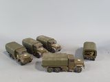 several toy army vehicles are lined up in a row on a white surface
