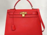 a red leather handbag with a gold lock on the handle
