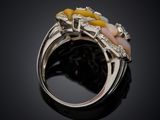 a close up of a ring with yellow and white stones on a black surface