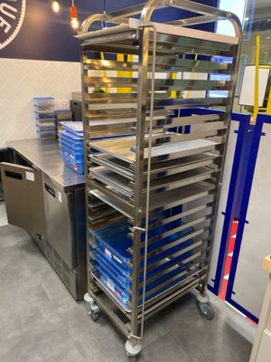 many trays of food on a metal cart in the kitchen