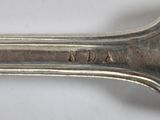 an old silver spoon with a handle on a white surface
