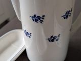 a white pitcher with blue flowers on it sitting on a table