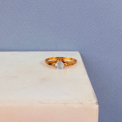 un gros plan d'une bague en or surmontée d'un diamant blanc