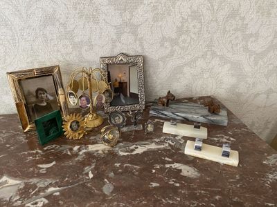 une table sur laquelle se trouvent un cadre photo, un cadre photo, un bougeoir, un cadre photo et d'autres objets