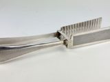 a silver plated comb with a handle on a white surface