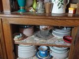 une armoire en bois sur laquelle sont posées de nombreuses assiettes et tasses