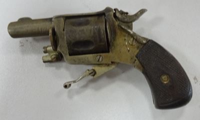 un petit revolver avec une crosse en bois posé sur une surface blanche