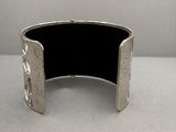 une photo d'un bracelet manchette en argent posé sur une table