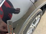 a person holding a ruler in front of a car