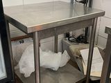 une table en acier inoxydable avec une porte en verre dans une cuisine