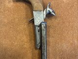 un vieux pistolet avec une poignée en bois sur une surface brune