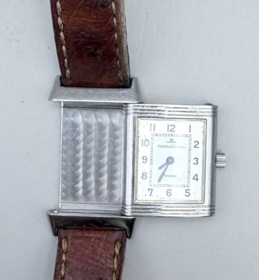 une montre argentée avec un bracelet marron sur un fond blanc