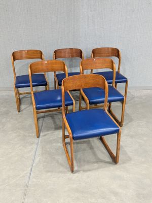 six chairs with blue leather seats in a room with a wall in the background
