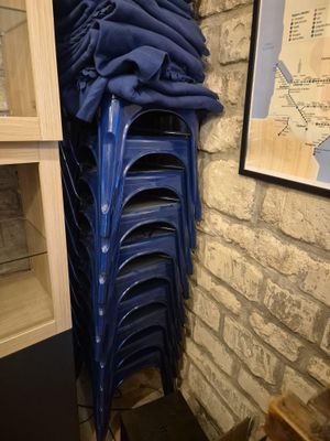 des chaises en plastique bleues empilées les unes sur les autres devant un mur de briques