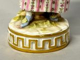 a figurine of a woman in a pink dress and blue shoes