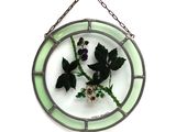 une plaque de verre sur laquelle est représentée une fleur, suspendue à une chaîne