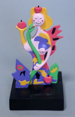 une figurine représentant une femme tenant une pomme à la main