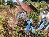 a rusted motorcycle sitting in a field of weeds