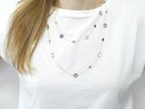 the woman is wearing a white t - shirt and a multi - colored necklace