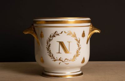 un vase blanc et doré sur lequel figure la lettre « n »