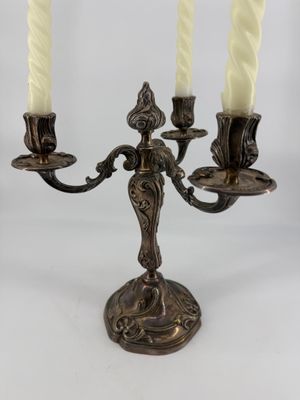an antique brass candelab with three candles on a white background