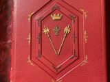 an open red book with a gold crown on top of it