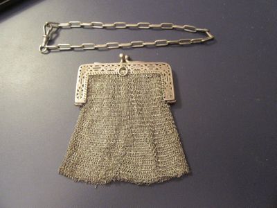 a silver purse with a chain around it on a table
