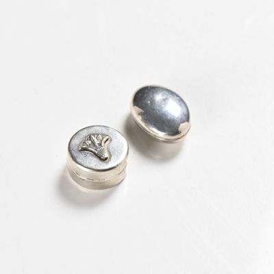 pair of silver buttons on white surface with one button facing the camera