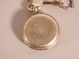 a silver pocket watch with a key chain attached to it