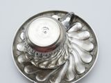 a silver cup and saucer on a silver plate