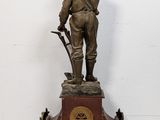 bronze statue of a man with a sword and a clock on a stand