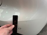 a person holding a remote control in front of a white car