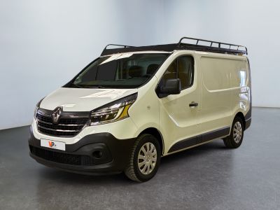 La camionnette blanche est garée dans une grande pièce au plafond noir.