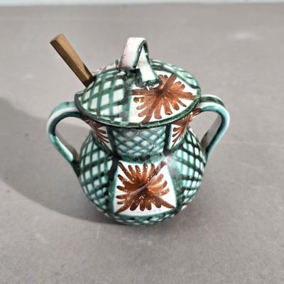 une petite théière avec une anse en bois posée sur une table