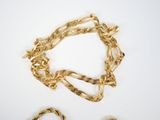 two pieces of gold chains and a bracelet on a white surface