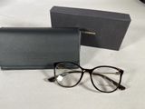 des lunettes de soleil et leur étui posés sur une table blanche, à côté d'une boîte noire