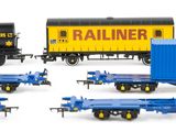 several toy train cars and trailers are lined up on a white surface