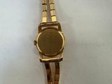 an image of a gold watch sitting on a white surface