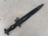 a close up of a knife on a white surface with a black handle