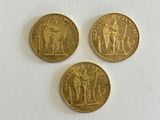 three gold coins sitting on top of a white surface next to each other