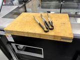 une planche à découper sur laquelle sont posés des couteaux, dans une cuisine